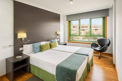 a bedroom with a bed and a chair and a window at Lanzahost Oceanis XXI in Arrecife
