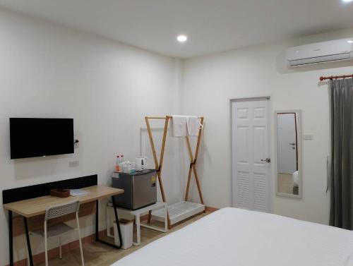 1 dormitorio con 1 cama, escritorio y TV en อาม่า อพาร์ทเมนต์ Ama Apartment, en Ban Phai