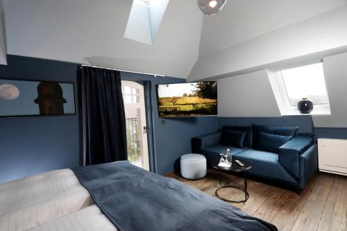 a bedroom with a blue bed and a couch at REINHARDTs HOTEL in Buchen