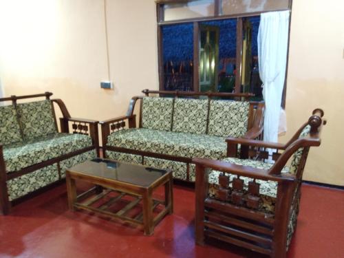 a living room with two couches and a table at Wilpattu Green Cabin in Achchamulai