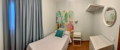 Una pequeña habitación con una cama y un espejo. en VIANYMAR APARTAMENTOS, en El Médano