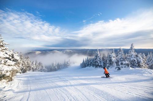a person is skiing down a snow covered slope at Le Boisé (Les Manoirs) Mont-Tremblant in Mont-Tremblant