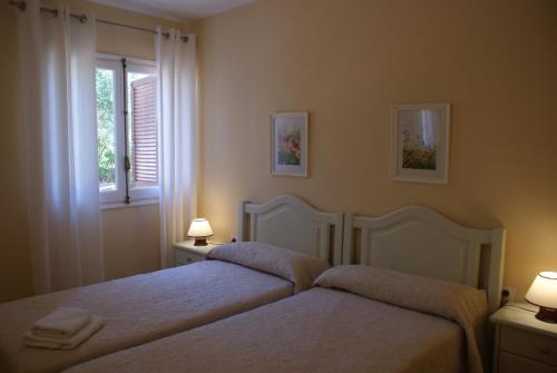 two beds in a bedroom with two lamps and a window at Villa Isabel in Son Bou