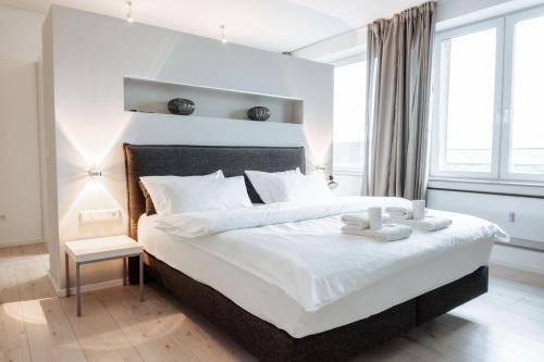 Un dormitorio con una gran cama blanca con una vela. en Luxuriöses Loft über den Dächern Münsters 150 m² en Münster