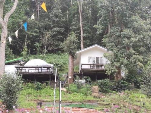 a house with a gazebo next to a forest at เตนท์โดมชายดอย ดอยแม่แจ๋ม ลำปาง in Ban Mai