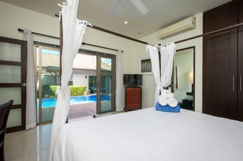a bedroom with a large bed with white curtains at VILLA ADONARA | Private Pool | Kokyang Estate by Tropiclook | Nai Harn beach in Nai Harn Beach
