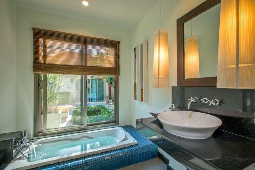 a bathroom with a tub and a sink and a window at VILLA ADONARA | Private Pool | Kokyang Estate by Tropiclook | Nai Harn beach in Nai Harn Beach