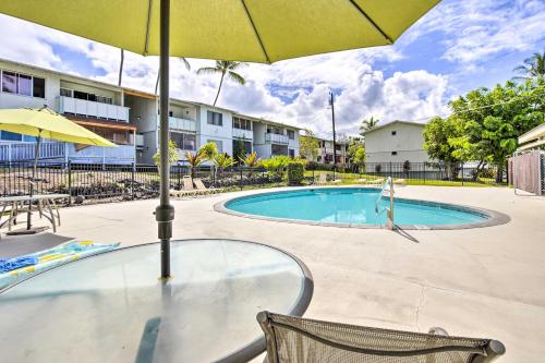 a table with an umbrella next to a swimming pool at Lanai and Community Pool Access Sunny Central Condo in Kailua-Kona
