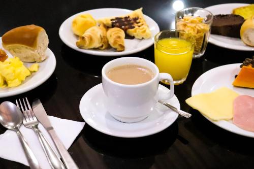 una mesa con platos de comida y una taza de café en Pousada Tia Leonor, en Gramado