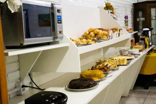 una línea de buffet con diferentes tipos de comida en platos en Pousada Tia Leonor, en Gramado