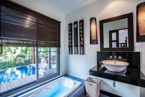 a bathroom with a tub and a sink and a pool at VILLA BUTON | Private Pool | Kokyang Estate by Tropiclook | Nai harn beach in Nai Harn Beach