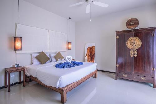 a bedroom with a large bed and a wooden cabinet at VILLA BUTON | Private Pool | Kokyang Estate by Tropiclook | Nai harn beach in Nai Harn Beach