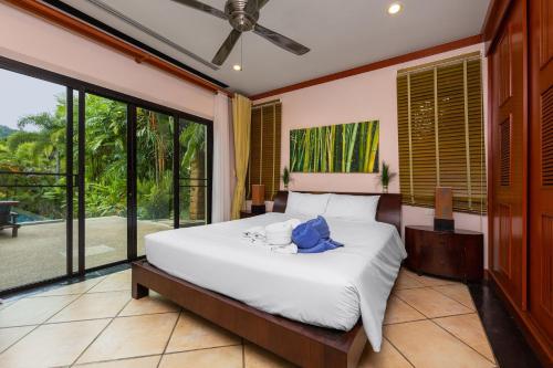 1 dormitorio con cama y ventana grande en VILLA RAAS | Private Pool | Baan Bua Estate by Tropiclook | Naiharn beach, en Nai Harn Beach