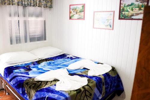 een slaapkamer met een bed met een blauwe deken bij Pousada Tia Leonor in Gramado
