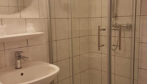 y baño con ducha y lavamanos. en Hôtel La Charbonnade en Dudelange