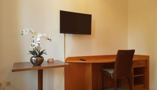 Habitación con escritorio y TV en la pared. en Hôtel La Charbonnade en Dudelange