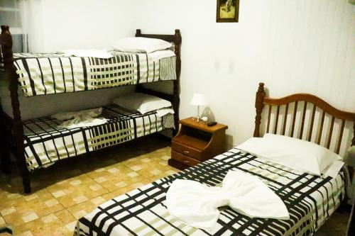 Dos camas en una habitación con un gato sobre ellas en Pousada Tia Leonor, en Gramado