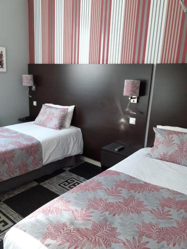 two beds in a room with red and white stripes at Logis Hotel - Le Charleston in Le Mans