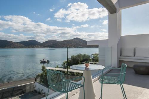 a balcony with a table and chairs and a boat in the water at Villa Mimaze Minimalist Living in Elounda