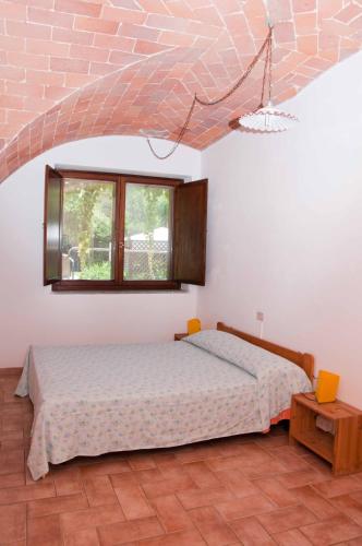 a bedroom with a bed and a window at Podere Valmarina in Follonica