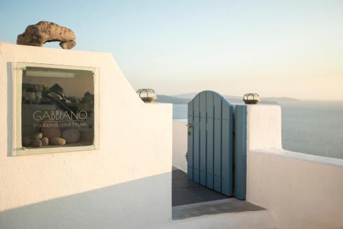 a blue door on the side of a white building at Gabbiano Traditional Cave Houses in Oia