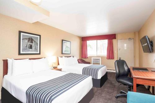 a hotel room with two beds and a desk at Sandman Inn Princeton in Princeton