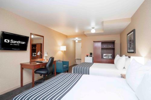 a hotel room with two beds and a desk at Sandman Inn Princeton in Princeton