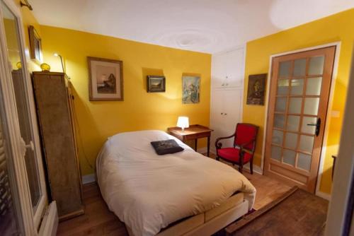 - une chambre avec des murs jaunes, un lit et un fauteuil rouge dans l'établissement Very French Two Bedroom in the Heart of Paris, à Paris
