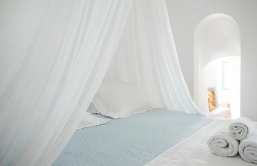 a white bedroom with a bed with towels on it at Gabbiano Traditional Cave Houses in Oia