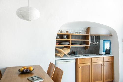a kitchen with a table with a bowl of fruit on it at Gabbiano Traditional Cave Houses in Oia
