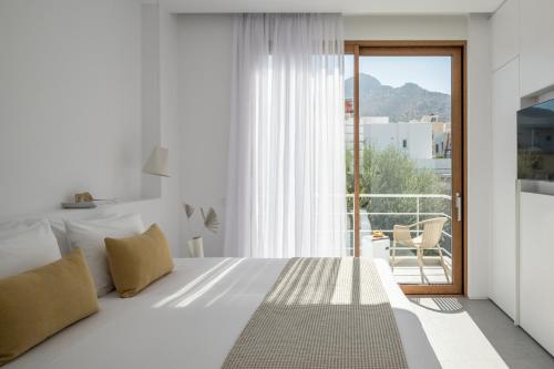 a white bedroom with a bed and a balcony at Villa Mimaze Minimalist Living in Elounda