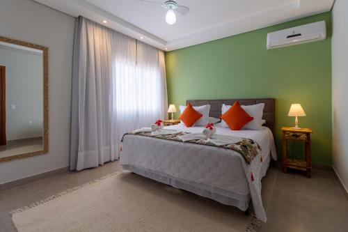a bedroom with a bed with orange pillows and a mirror at Pousada Casa Cajá in Arraial d'Ajuda