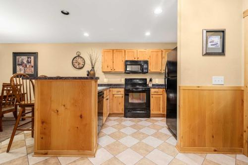 a kitchen with wooden cabinets and a black refrigerator at Gull Lake All-Season Getaway with Private Deck in Lake Shore