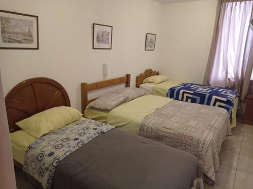 a room with three beds in a room at HOSTAL PARIS in Piura
