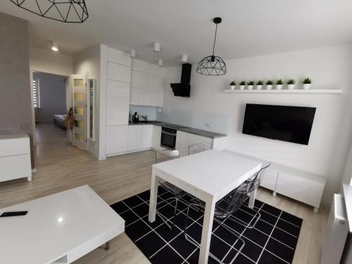 a living room with a white table and a kitchen at Elen & K in Polkowice