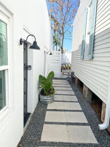 a walkway next to a white house with a plant at The Pink Room at Emily's On The Island in Galveston
