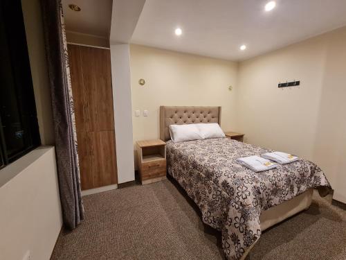 1 dormitorio pequeño con 1 cama y armario de madera en Hostal Tuki Huancayo, en Huancayo