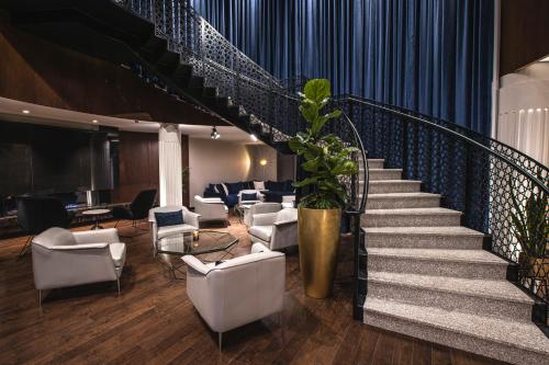a lobby with a staircase with white chairs and a plant at Le Capitole Hotel in Quebec City