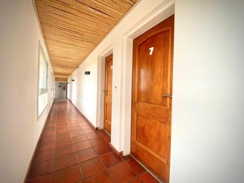 a hallway with a wooden door and a tile floor at Hotel Colores in Merlo