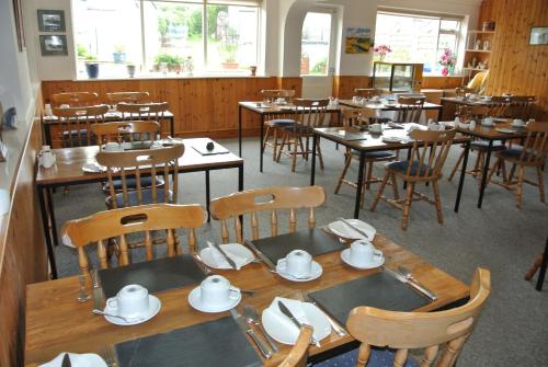 una sala da pranzo con tavoli e sedie in legno e stoviglie di Old Castle Farm Guest House a Brecon