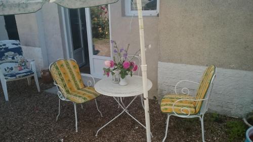 2 chaises et une table avec un vase de fleurs dans l'établissement GITE INSOLITE Le Pressoir en Touraine, à Vallières-les-Grandes