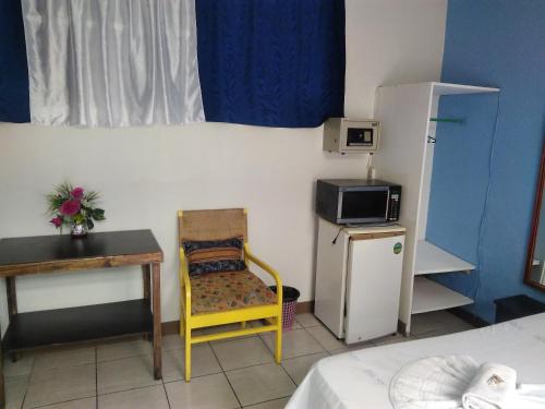Habitación pequeña con mesa, silla y nevera. en Hotel Marruecos C.R. en San José