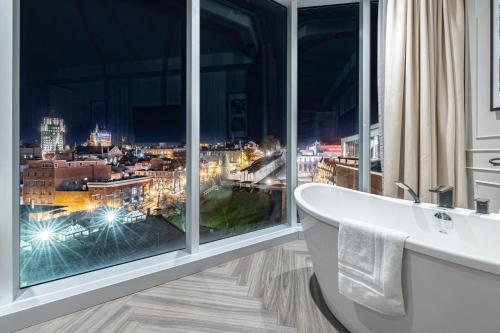 a bathroom with a bath tub and a large window at Le Capitole Hotel in Quebec City
