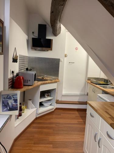 une cuisine mansardée avec des placards blancs et un escalier dans l'établissement Gîte Old Car Home hyper centre-ville, à Compiègne