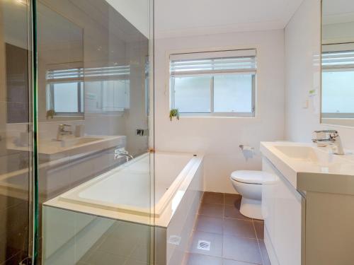 a bathroom with a tub and a toilet and a sink at Kiama Sunrise Kiama in Kiama