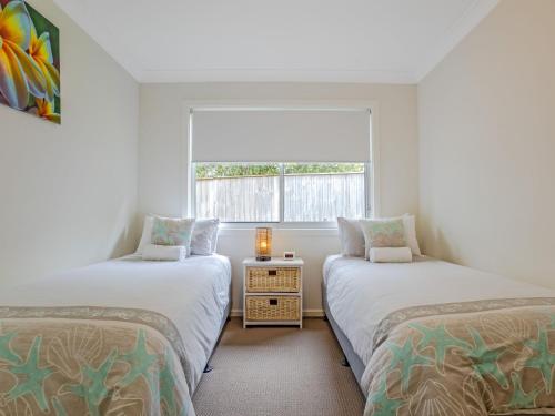 two beds in a room with a window at Kiama Sunrise Kiama in Kiama