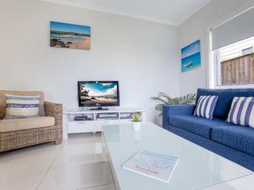 a living room with a blue couch and a tv at Kiama Sunrise Kiama in Kiama