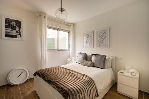 Habitación blanca con cama y reloj en Stylish New 1 bedroom apartment in juan les pins, en Antibes