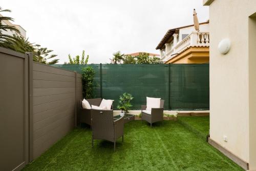 a patio with chairs and a fence with grass at Stylish New 1 bedroom apartment in juan les pins in Antibes
