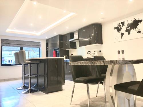 a kitchen with black cabinets and black bar stools at Millstream Mews - Fiddlesticks in Bakewell